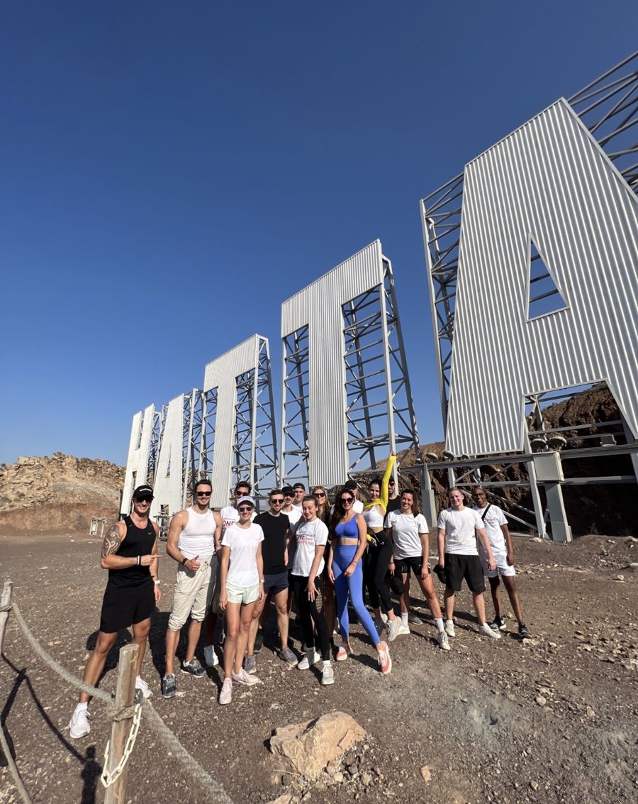 Team group photo in front of the giant Hatta sign